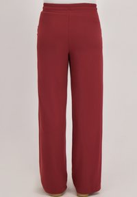 Rode wijde broekspijpen gemaakt van zachte stof. Ontworpen met een elastische tailleband voor comfort. Kenmerkt zich door een effen afwerking zonder zichtbare patronen of accenten.