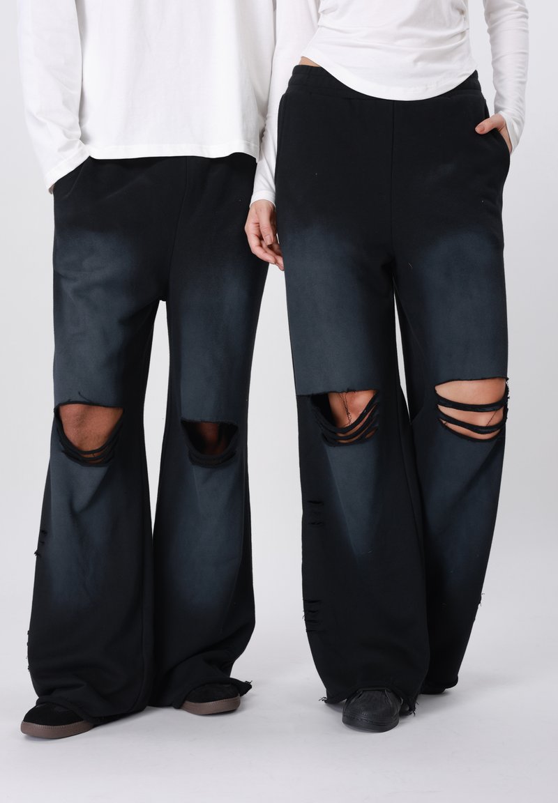 Μαύρο παντελόνι με φαρδύ πόδι και εμφανή κοψίματα στα γόνατα, με διαβαθμισμένο εφέ από σκούρο σε ανοιχτό. Υφασμα με υφή και άνετη εφαρμογή.