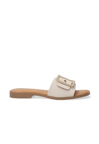 Beige læder slide sandal med en flad sål, der har et fremtrædende guldspænde og en struktureret overflade.