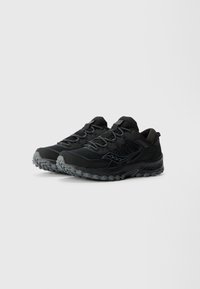 Chaussures de sport noires avec une tige en mesh, une semelle en caoutchouc et un motif de grip texturé. Présente des accents gris contrastants et un renfort à l'avant.
