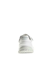 Zapatilla deportiva blanca con la parte trasera redondeada, material sintético suave, logo en el talón y suela de goma con patrón. Diseño minimalista sin acentos adicionales.