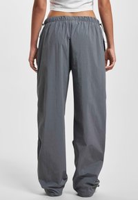 Pantaloni grigi leggeri con coulisse, dal taglio morbido e vita elasticizzata, caratterizzati da gambe leggermente affusolate e una texture liscia.