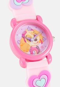 Reloj infantil rosa con una esfera circular que presenta un perro animado. Correa de silicona rosa suave con acentos en forma de corazón. Marcadores de hora simples.