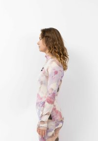 Lange mouw top van zachte stof met een meerkleurig aquarelpatroon. Hoge kraag, aansluitend ontwerp en een bedrukte logo op de voorkant.