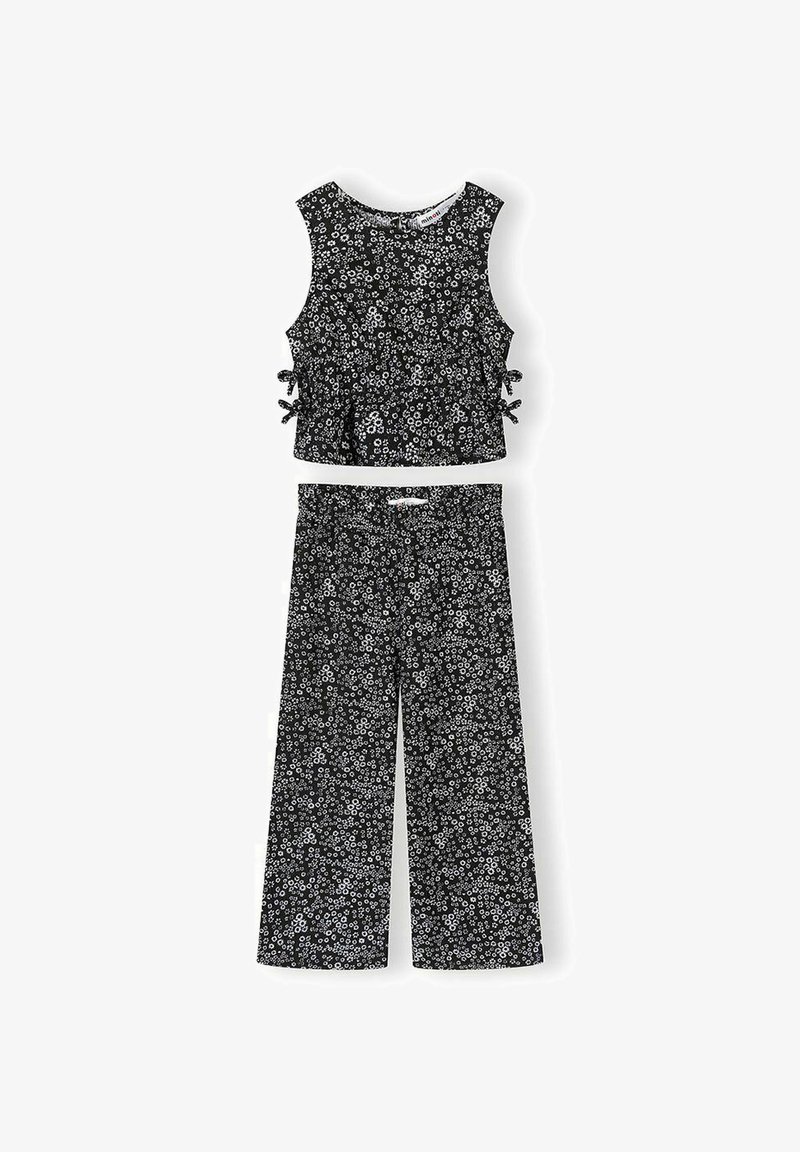 Haut court noir sans manches avec liens sur les côtés et pantalon large assorti, tous deux ornés d'un petit motif floral blanc.