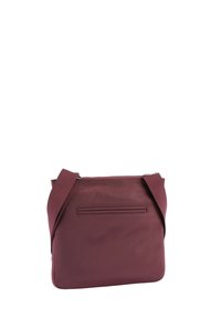 Bordová crossbody taška z texturované látky se zipovým uzavřením, s plochou kapsou na zadní straně a nastavitelným popruhem.