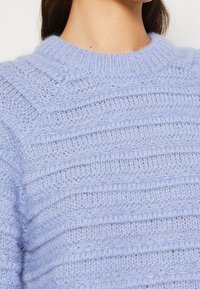 Pullover lavorato a maglia blu chiaro con scollo rotondo, caratterizzato da strisce orizzontali testurizzate e un tessuto morbido e soffice.