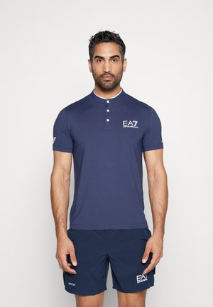 Navy polo shirt with a slim fit, short sleeves, a buttoned collar, and white accent detailing. Features EA7 logo on the chest and sleeve.