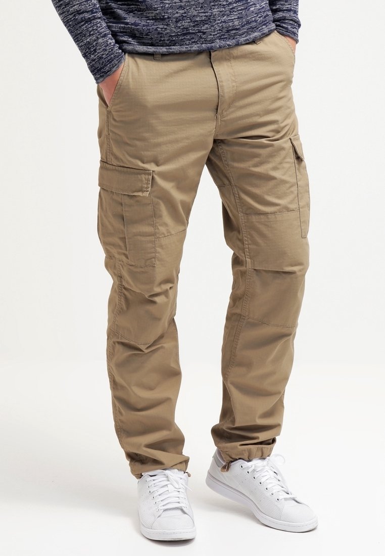 Pantaloni cargo di un khaki chiaro con multiple tasche, design a gamba dritta e un tessuto liscio e strutturato. Abbinati a sneakers bianche.