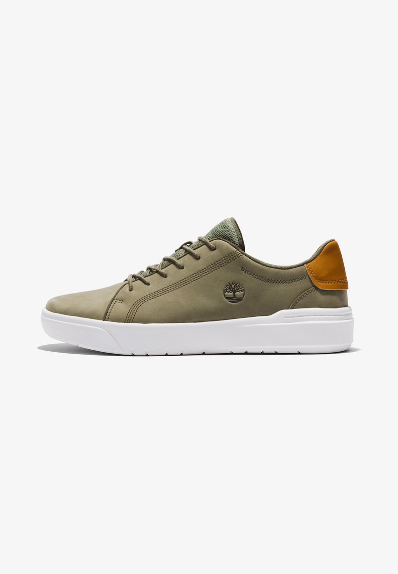 Zielone skórzane sneakersy z białą gumową podeszwą, z brązowym skórzanym akcentem na pięcie i dekoracyjnym przeszyciem. Logo wytłoczone z boku.