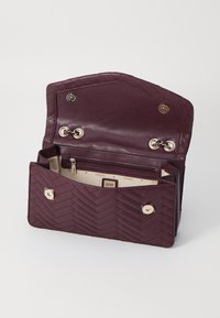 Bordeaux-farvet faux læderpunge, quilted hørmønster, sølvhardware, trykknap- og lynlåslukninger, flere rum og beige indvendig.