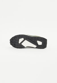 Svart gummisåle til sneakers med teksturert design. Har en hvit mellomsåle og mørkegrønne detaljer. Forsterket hæl for støtte.