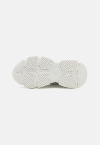 Weißer Sneaker mit einer strukturierten Gummisohle, die ein Fischgrätmuster für bessere Griffigkeit bietet, einer abgerundeten Zehenpartie und einer glatten Oberfläche.
