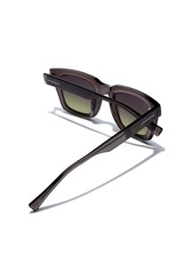 Sonnenbrille mit einem dunkelbraunen, glanzvollen Kunststoffrahmen, grünen Verlaufslinsen und schlanken, zulaufenden Bügeln mit dem Markennamen "HAWKERS."