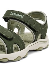 Grüne Sandale mit verstellbaren Riemen, gefertigt aus synthetischem Material. Verfügt über eine gepolsterte Innensohle, eine Gummiaußensohle und strukturierte Details.