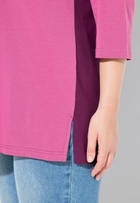 Roze en paarse color-blocked shirt met een zijsplit, gemaakt van zachte stof. Beschikt over een ronde zoom en driekwart mouwen.