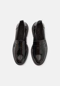 Chaussures à enfiler en cuir verni noir avec un bout arrondi, des panneaux latéraux élastiques, et un logo embossé à l'avant. Semelle extérieure en caoutchouc texturé.