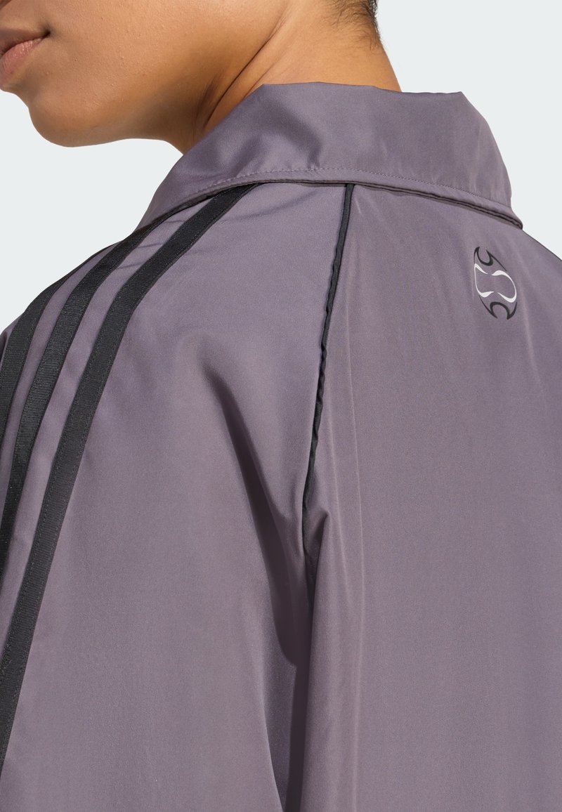 Purple jacket featuring a collar, black side stripes, and a logo on the back. The fabric appears smooth with a slightly shiny texture.