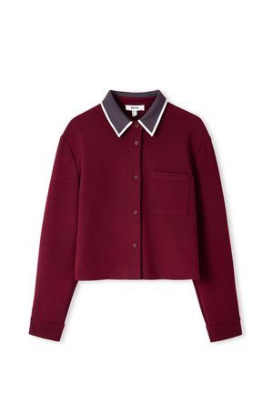 Bordeaux kleurige cropped shirt met een knoopsluiting aan de voorkant, contrasterende donkergrijze kraag, witte piping en een enkele opgestikte zak aan de linkerkant.