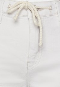 Shorts en denim blanc avec un cordon de serrage tressé blanc à la taille, dotés d'une poche avant et de subtils détails de couture.