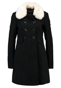 Manteau noir croisé avec six boutons argentés et un large col en fausse fourrure blanche, manches longues et ourlet à hauteur des hanches.