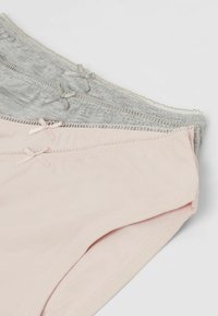 Drei gefaltete Damen-Cotton-Pants in Hellrosa und Grau, jeweils mit einer kleinen dekorativen Schleife am Bund.
