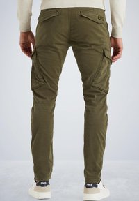 Olivgrüne Cargo-Hosen mit mehreren Seitentaschen, schmal zulaufenden Beinen und einer weichen Textur. Getragen mit weißen und beigen Sneakers, Rückansicht gezeigt.