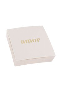 Scatola di gioielli quadrata, di un rosa pallido, con una superficie liscia e una leggera lucentezza. Il coperchio presenta la parola "amor" in oro, scritta con un carattere moderno.