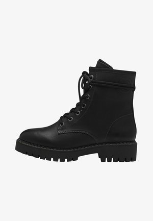Bottines en cuir noir avec un laçage à l'avant, bout rond et semelle épaisse et robuste. Col rembourré et détail de logo circulaire sur le côté.