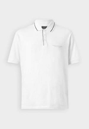 Balts polo krekls ar apkakli, kuru rotā melnas maliņas apkaklī un pogu rindā. Iekļauj trīs pogas un smalku logo uz krūšu daļas.