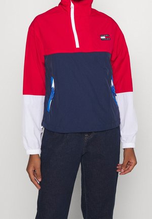 Pulloverjack met lange mouwen, rode bovenkant, marineblauw middenstuk, witte mouwen, blauwe ritszakken en "Tommy Jeans"-logo op de borst.