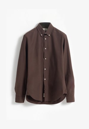 Camisa de manga larga marrón, hecha de tejido suave, con cuello abotonado, botones blancos y un dobladillo curvado.