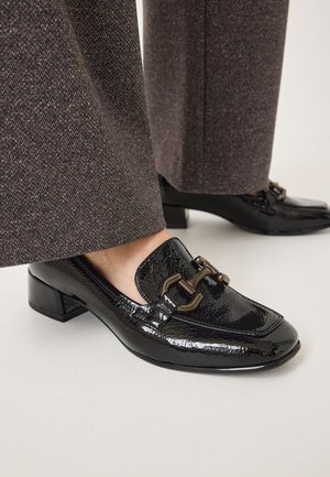 Svarta lackskinnsloafers med fyrkantig tå och liten klack, prydda med dekorativa metallkedjeaccents och texturerade detaljer.