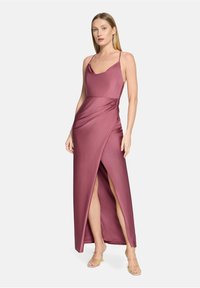 Robe maxi rose profond avec encolure drap ée et fines bretelles, dotée de fronces latérales et de hautes fentes. Matière satinée avec texture lisse.