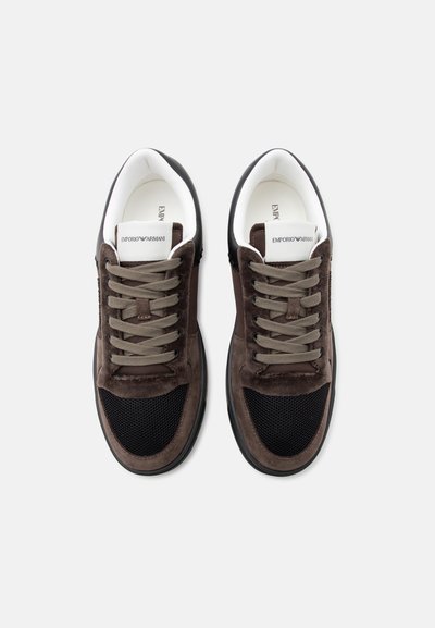 Ζευγάρι καφέ και μαύρα sneakers Emporio Armani με κορδόνια, λευκή εσωτερική επένδυση και λογότυπο στη γλώσσα, που φαίνονται από πάνω σε λευκό φόντο.