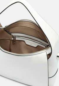 Biała skórzana torebka na zamek, z brązowym wnętrzem i kieszenią na zamek. Gładka tekstura i proste linie, minimalna ilość akcesoriów.