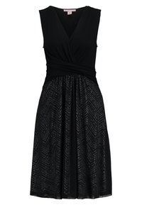 Musta mekko, jossa on kietaisukaulus ja hihaton muotoilu. Hameessa on tekstuuri, jossa on chevron-kuvio. Kevyt kangas, joka kohtaa virtaavan siluetin.