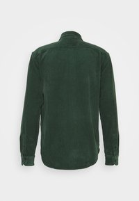 Tummanvihreä samettinen pitkähihaisuus paita napitettavilla hihansuilla, näkyy takaa tasaisella valkoisella taustalla.