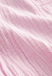 Tissu rose pâle avec un tissage doux et texturé, présentant des plis subtils et une surface lisse. Convient à diverses applications textiles.