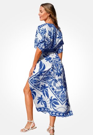 Maxi-jurk in wit met een blauwe tropische print, met een relaxte pasvorm, elastische taille, korte mouwen en een zijsplit voor comfort.