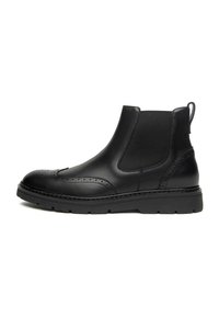 Bottes Chelsea en cuir noir avec des détails de brogue, des panneaux élastiques sur les côtés et une épaisse semelle en caoutchouc noir. Texture lisse, design à bout rond.