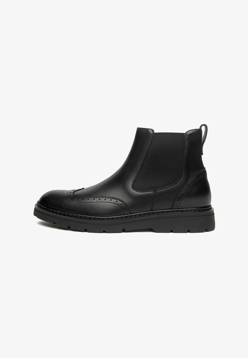 Bottes Chelsea en cuir noir avec des détails de brogue, des panneaux élastiques sur les côtés et une épaisse semelle en caoutchouc noir. Texture lisse, design à bout rond.