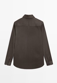 Chemise à manches longues marron foncé avec des rayures verticales subtiles, des poignets boutonnés et un ourlet incurvé, vue de dos sur un fond blanc.