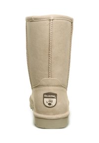 Beige Wildleder-Ankle-Boot mit runder Zehenkappe, genähten Details und Gummisohle. Mit einem kleinen Bärenpfoten-Logo an der Ferse.