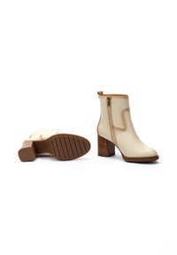 Cream leather ankle boots with a rounded toe and a side zipper. Stacked wooden heel, textured sole, and light stitching detail.