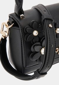 Black faux leather handbag featuring floral appliqués with pearl accents, gold hardware, and a detachable shoulder strap.