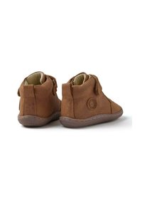 Botas de tobillo de cuero marrón con un acabado texturizado, cremalleras laterales y un detalle de logo circular en el talón exterior. Forro suave y suela flexible.