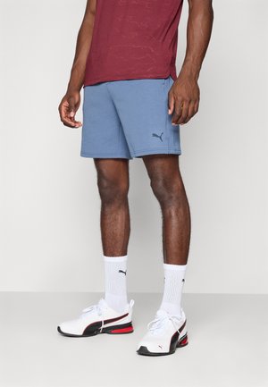 Light blue athletic shorts with a textured finish, paired with white sneakers featuring red and black accents, and white crew socks.