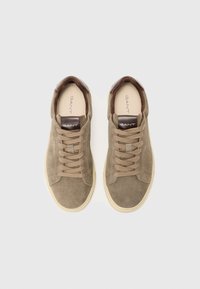 Adidași din suede maro cu talpă din cauciuc, având un accent din piele maro la călcâi și șireturi plate. Logo pe limbă și pe lateral. Design minimalist.