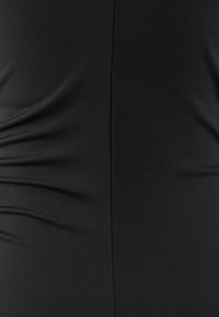 Černá tkanina s texturovaným povrchem má na jedné straně nabírané detaily. Materiál je hladký a lehký, vhodný pro zavěšení.